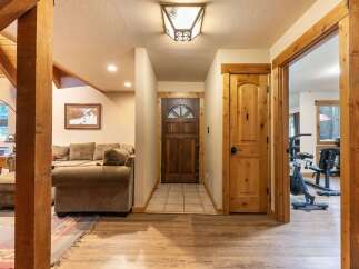 Step into this inviting entryway featuring a rustic wooden front door and a cozy living area with plush seating.