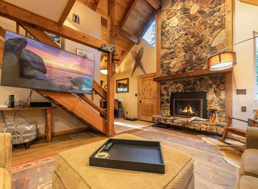 Experience rustic charm in this inviting living room, featuring a grand stone fireplace and exposed wooden beams that create a cozy, lodge-like atmosphere.