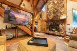 Experience rustic charm in this inviting living room, featuring a grand stone fireplace and exposed wooden beams that create a cozy, lodge-like atmosphere.