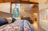 Experience rustic charm in this cozy bedroom, featuring a beautifully crafted wooden headboard and a striking geometric-patterned blanket.