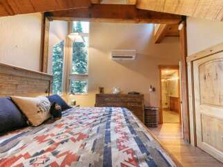 Experience rustic charm in this cozy bedroom, featuring a beautifully crafted wooden headboard and a striking geometric-patterned blanket.