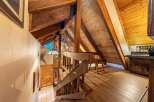 Experience rustic charm in this mountain home featuring exposed wooden beams and a stone accent wall.