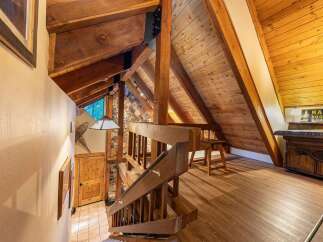 Experience rustic charm in this mountain home featuring exposed wooden beams and a stone accent wall.