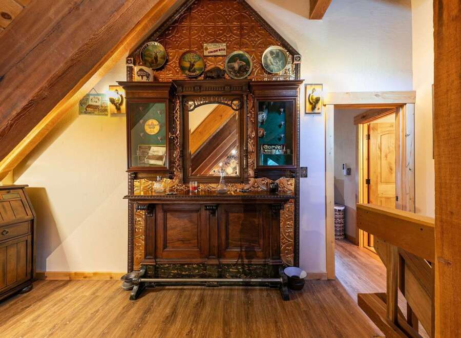 Step into a rustic haven with this charming bar area, featuring a beautifully ornate wooden cabinet with mirrored insets and decorative tin paneling.