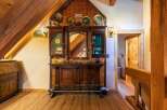 Step into a rustic haven with this charming bar area, featuring a beautifully ornate wooden cabinet with mirrored insets and decorative tin paneling.