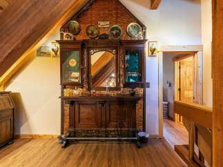 Step into a rustic haven with this charming bar area, featuring a beautifully ornate wooden cabinet with mirrored insets and decorative tin paneling.