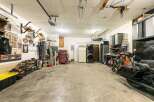 This spacious garage offers ample storage solutions, including shelving units and a red rolling tool chest, perfect for organizing your tools and equipment.