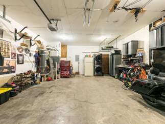 This spacious garage offers ample storage solutions, including shelving units and a red rolling tool chest, perfect for organizing your tools and equipment.