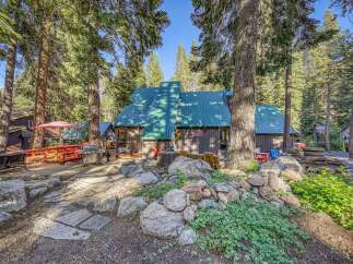 Escape to this charming cabin nestled among tall pine trees, offering a perfect blend of rustic appeal and outdoor living.