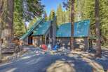 Nestled amidst tall pine trees, this charming cabin features a distinctive green metal roof and a rustic exterior.