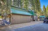 Discover this unique mountain home featuring a striking green metal roof and rustic siding, nestled amongst tall pine trees.
