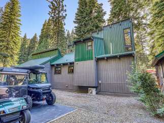 Discover this unique mountain retreat featuring a modern architectural design with striking green metal siding and a complementary gray wood exterior.