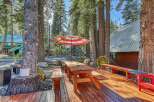 Enjoy outdoor living in this charming cabin setting, complete with a spacious wooden deck, picnic table, and umbrella.