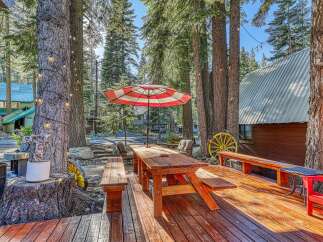 Enjoy outdoor living in this charming cabin setting, complete with a spacious wooden deck, picnic table, and umbrella.