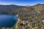 Experience the ultimate lakeside living with this stunning aerial view of a property nestled amidst a dense pine forest, offering direct access to a crystal-clear lake.