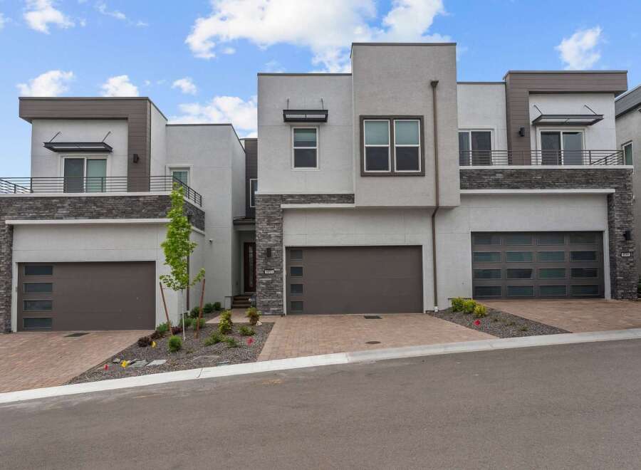 Discover modern luxury in this stunning townhome featuring a sleek stucco exterior and striking stone accents.