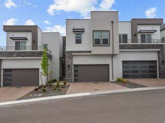 Discover modern luxury in this stunning townhome featuring a sleek stucco exterior and striking stone accents.