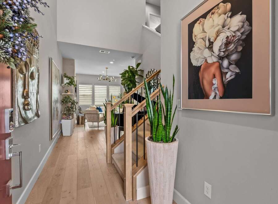 Step into this inviting entryway featuring a striking Buddha wall art and a modern staircase with elegant railings.