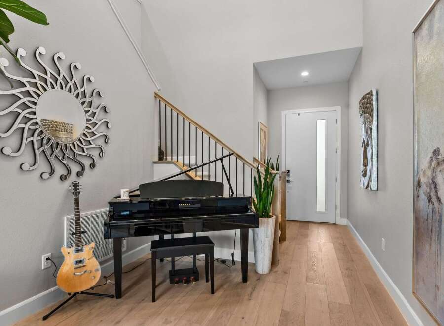 This elegant entryway features a stunning black grand piano, perfect for music lovers.