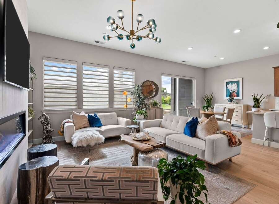 Experience modern living in this spacious open-concept living area, featuring a sleek fireplace and a stunning multi-bulb chandelier.