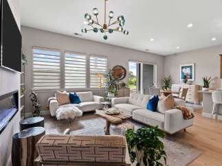 Experience modern living in this spacious open-concept living area, featuring a sleek fireplace and a stunning multi-bulb chandelier.