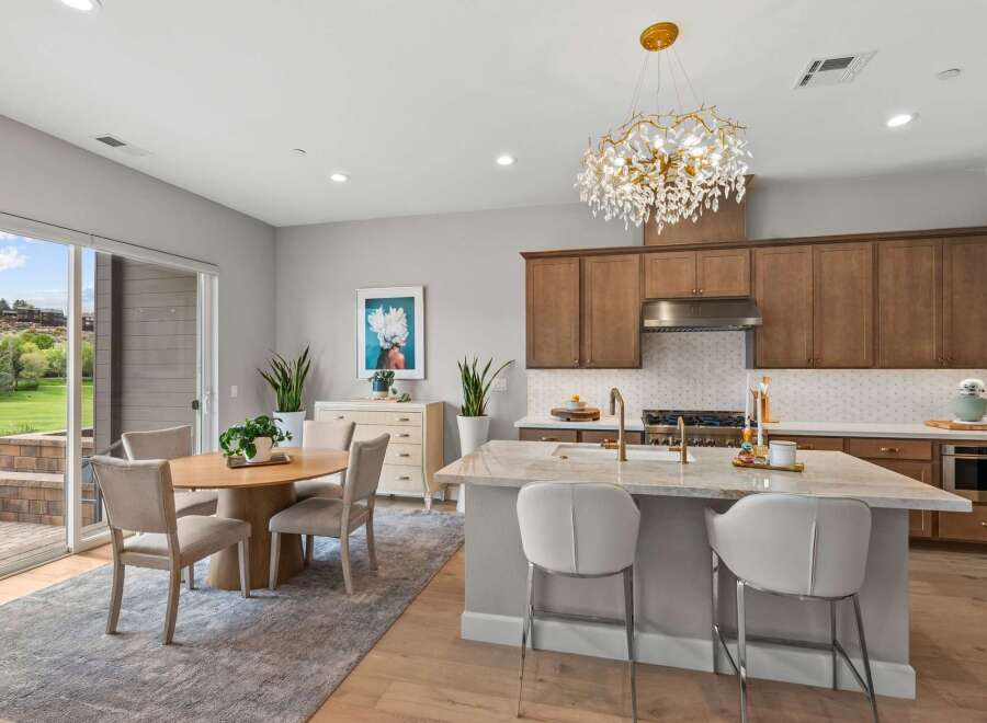 Experience modern living in this stunning kitchen and dining area, featuring a large marble island with bar seating and a beautiful crystal chandelier.