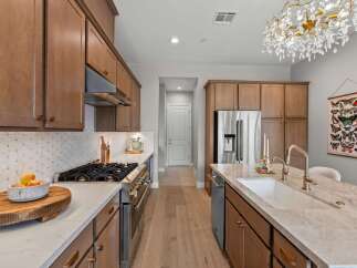 Experience luxury in this stunning kitchen featuring sleek, modern cabinetry and a spacious island with a farmhouse sink.