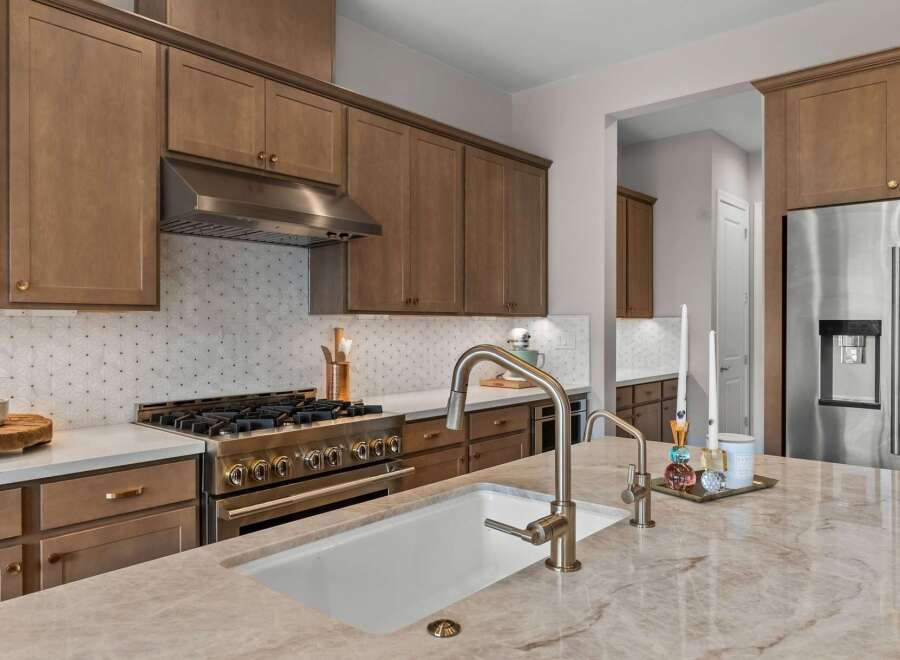 Experience luxury in this stunning kitchen, featuring elegant brown cabinetry and a sleek stainless steel range with a decorative backsplash.