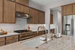 Experience luxury in this stunning kitchen, featuring elegant brown cabinetry and a sleek stainless steel range with a decorative backsplash.