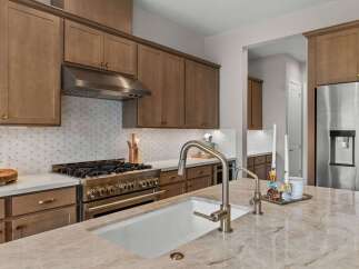 Experience luxury in this stunning kitchen, featuring elegant brown cabinetry and a sleek stainless steel range with a decorative backsplash.