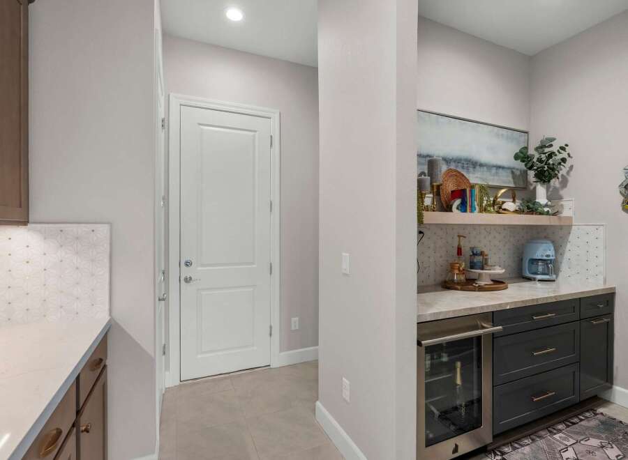 Discover this stylish wet bar, perfect for entertaining, featuring a built-in wine fridge and a chic coffee station.