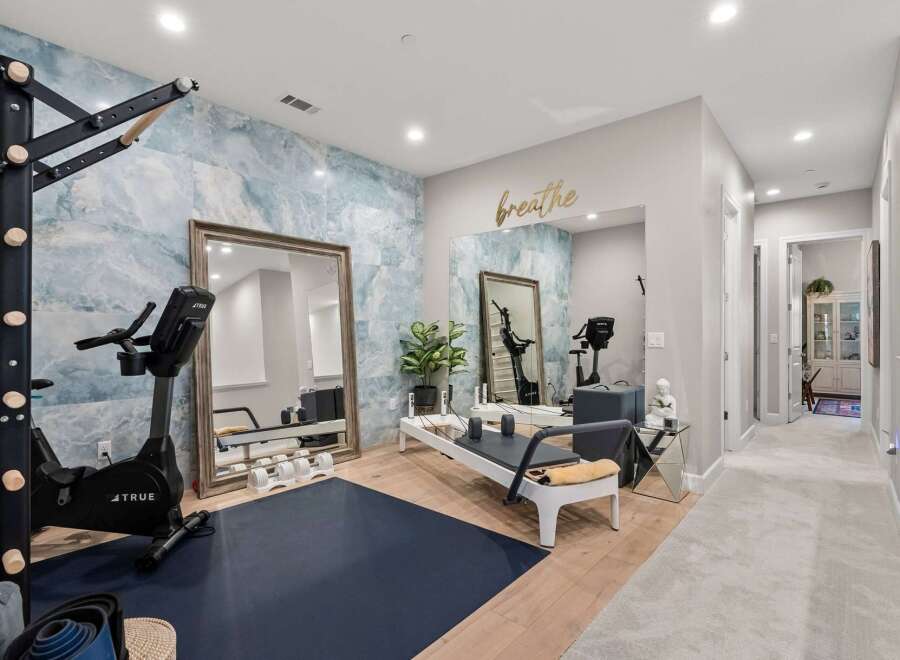 Transform your wellness routine in this dedicated home gym, featuring a high-end stationary bike and a Pilates reformer.