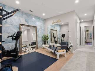 Transform your wellness routine in this dedicated home gym, featuring a high-end stationary bike and a Pilates reformer.