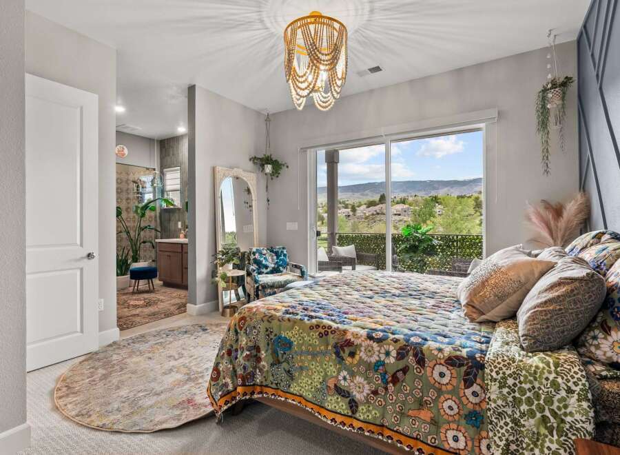 Experience bohemian luxury in this stunning bedroom featuring a vibrant, patterned quilt and a unique beaded chandelier.