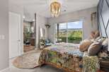 Experience bohemian luxury in this stunning bedroom featuring a vibrant, patterned quilt and a unique beaded chandelier.