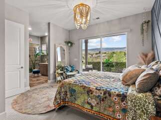 Experience bohemian luxury in this stunning bedroom featuring a vibrant, patterned quilt and a unique beaded chandelier.