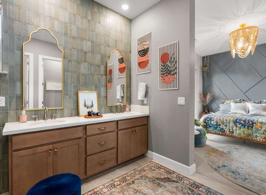 This stunning bathroom features a dual vanity with elegant gold-framed mirrors and a unique tiled backsplash.