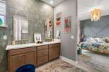 This stunning bathroom features a dual vanity with elegant gold-framed mirrors and a unique tiled backsplash.