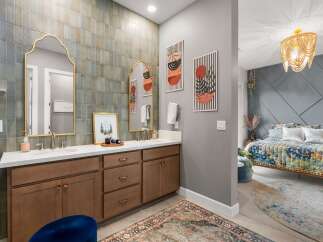 This stunning bathroom features a dual vanity with elegant gold-framed mirrors and a unique tiled backsplash.