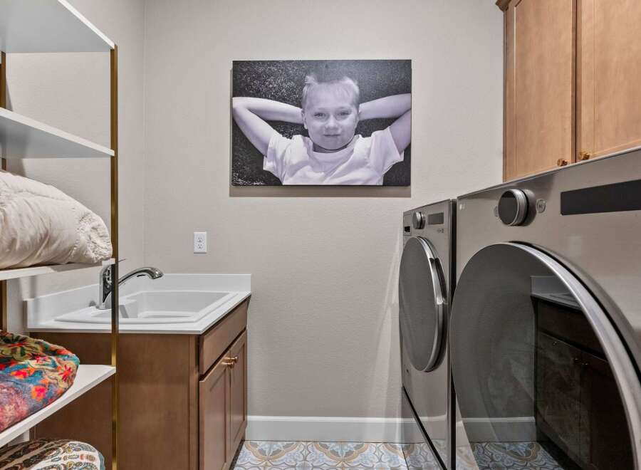 This laundry room offers a functional and stylish space with a deep sink and ample cabinet storage.