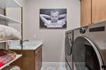 This laundry room offers a functional and stylish space with a deep sink and ample cabinet storage.