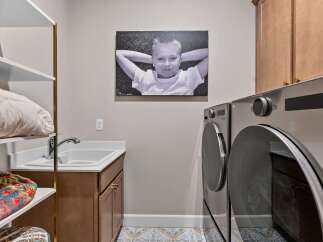 This laundry room offers a functional and stylish space with a deep sink and ample cabinet storage.