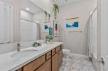 This modern bathroom features a spacious double vanity with a white quartz countertop and warm wood cabinetry.