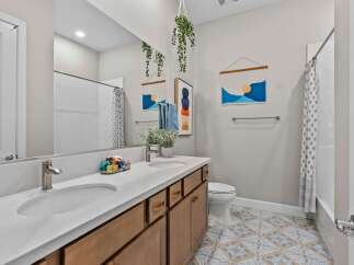 This modern bathroom features a spacious double vanity with a white quartz countertop and warm wood cabinetry.