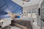 This bedroom features a striking blue accent wall with a geometric design, complemented by a plush tufted headboard and a comfortable gray comforter.