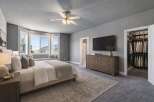 Experience luxury in this master bedroom featuring a spacious walk-in closet and a wall-mounted TV above a classic wooden dresser.