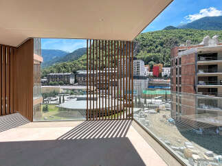 Experience modern living with this stunning balcony offering panoramic mountain views and a unique slatted wood design.