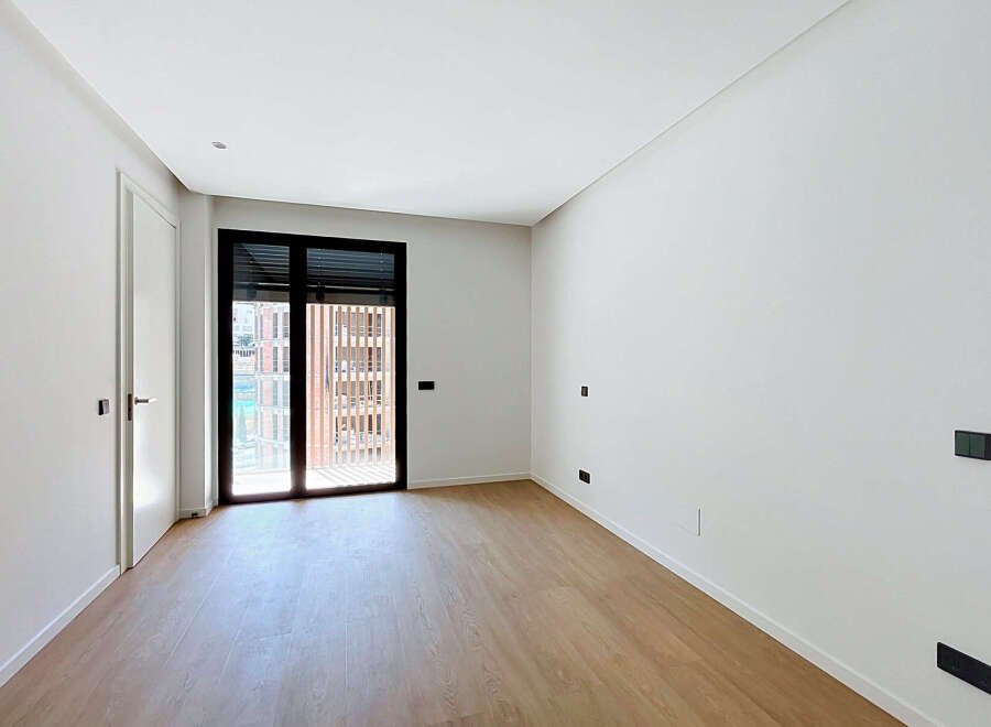 Discover this bright and airy room featuring a modern design with clean white walls and elegant light wood flooring.