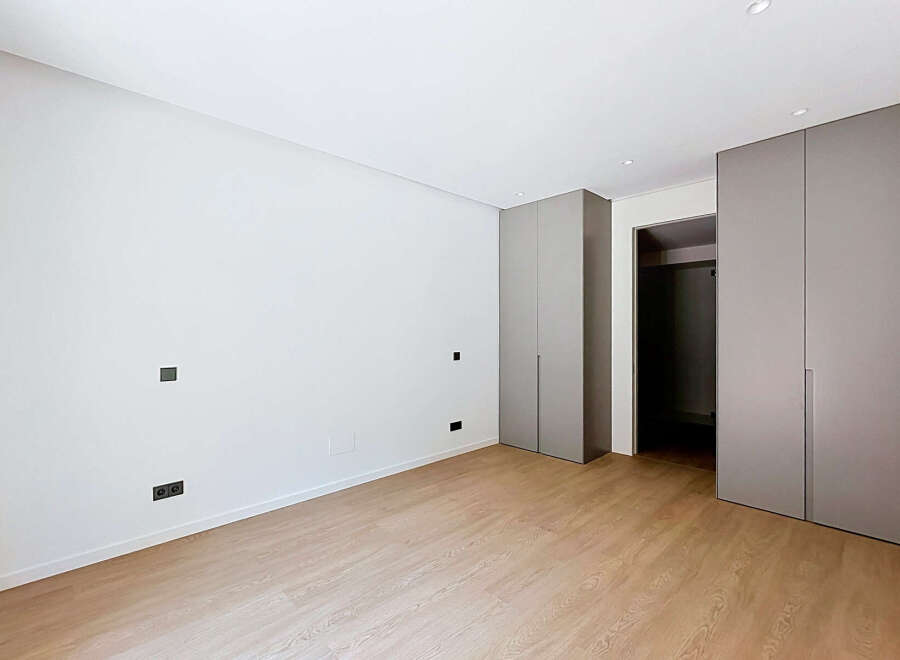 Discover modern living in this unfurnished bedroom, featuring sleek grey built-in wardrobes and a minimalist aesthetic.