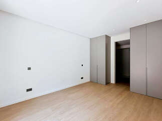 Discover modern living in this unfurnished bedroom, featuring sleek grey built-in wardrobes and a minimalist aesthetic.